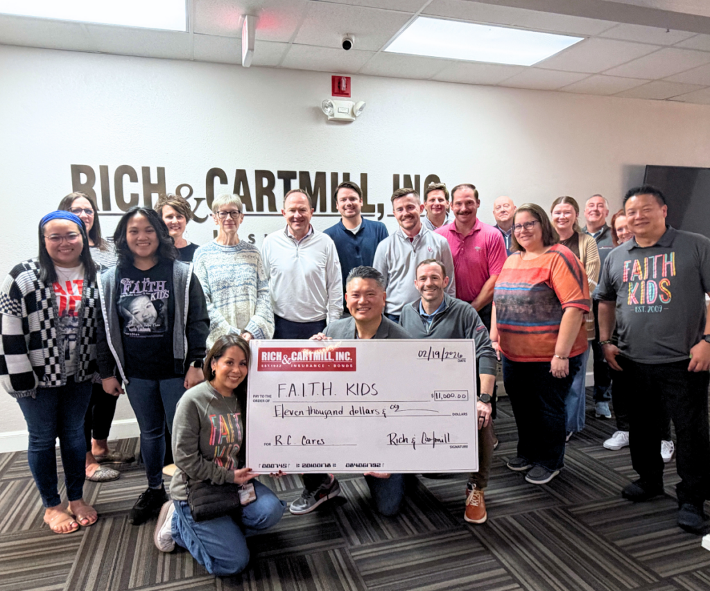 Photo of team holding check from Rich & Cartmill insurance.
