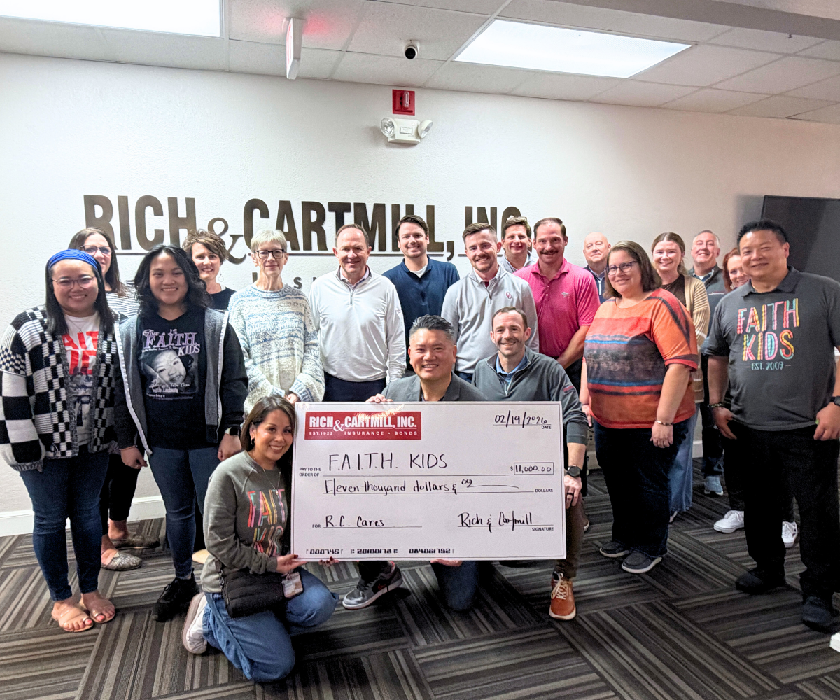Photo of team holding check from Rich & Cartmill insurance.