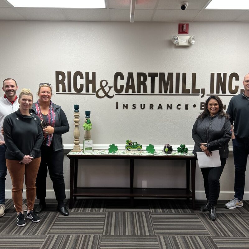 Group photo of the Warriors for Freedom team standing in front of the Rich & Cartmill sign