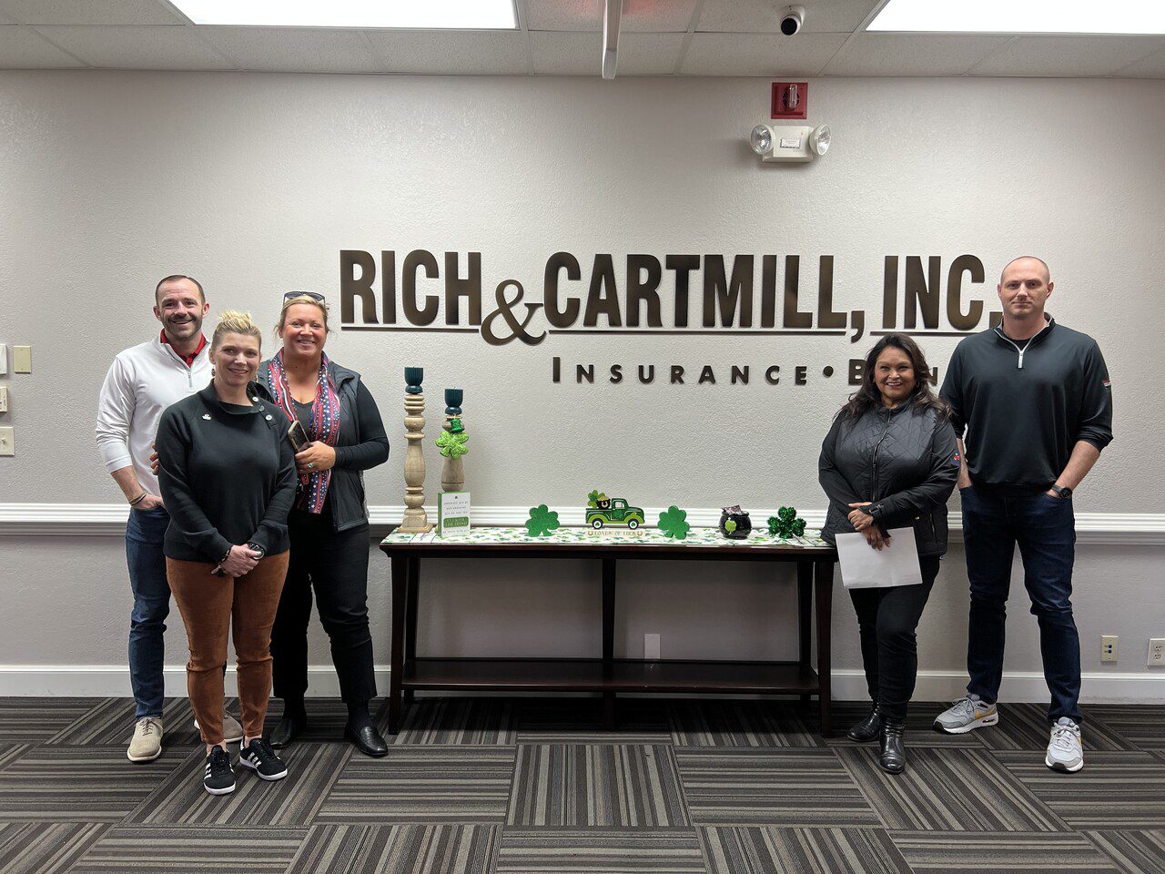 Group photo of the Warriors for Freedom team standing in front of the Rich & Cartmill sign