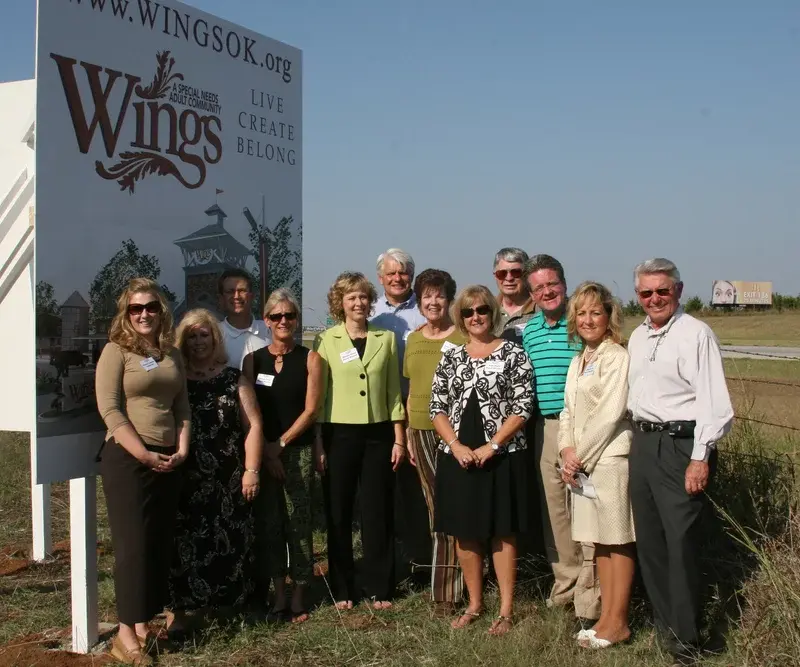 Group photo of the Wings OK team standing outside in front of the Wings OK sign.