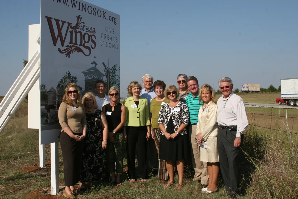Group photo of the Wings OK team standing outside in front of the Wings OK sign.